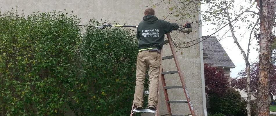 Lawn care professional in Delaware, OH, trimming shrubs on a property.