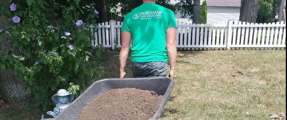 Professional service member lugging mulch for a landscape bed in Delaware, OH.