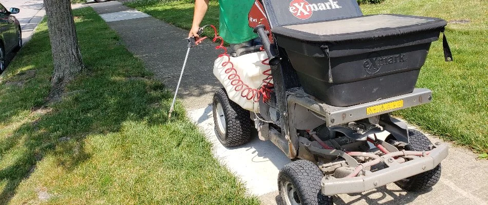 A professional in Delaware, OH, applying weed control near a sidewalk.