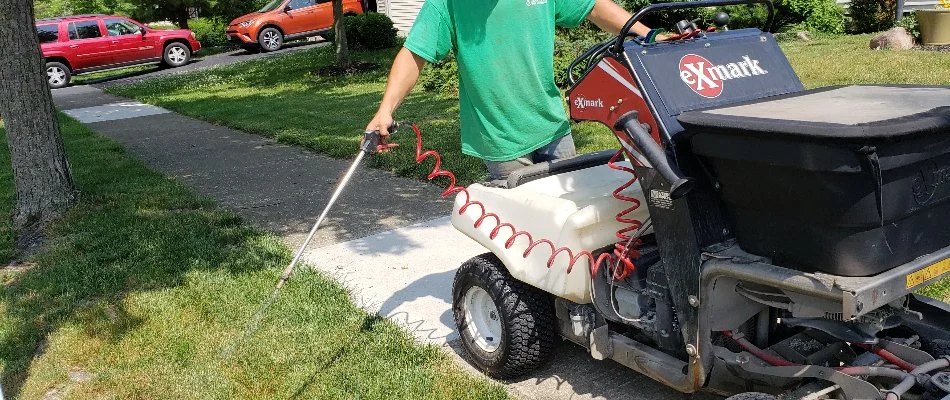 Lawn care employee spraying residential lawn in New Albany, OH.